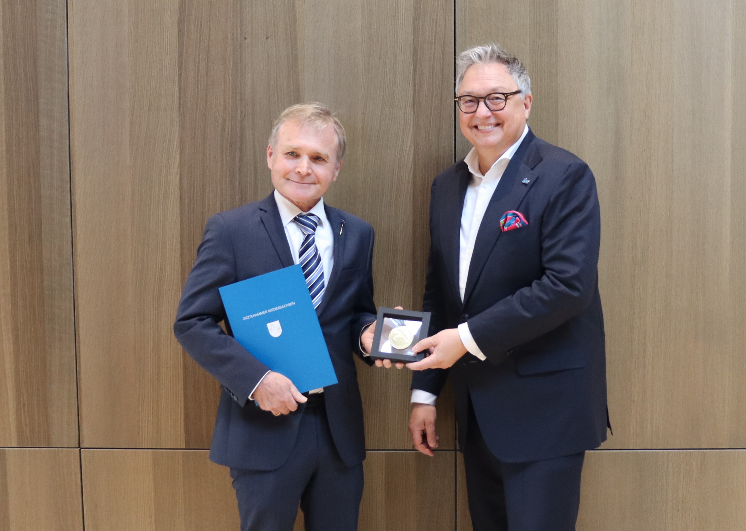 Der stellvertretende Präsident der Ärztekammer Niedersachsen und Vorsitzende der Bezirksstelle Hannover Dr. med. Thomas Buck (r.) überreicht die Ehrenplakette an den ehemaligen Präsidenten des Niedersächsischen Landesgesundheitsamts Dr. med. Matthias Pulz (l.).  